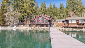 A waterfront property with a dock leading to a building with a red roof and large windows.