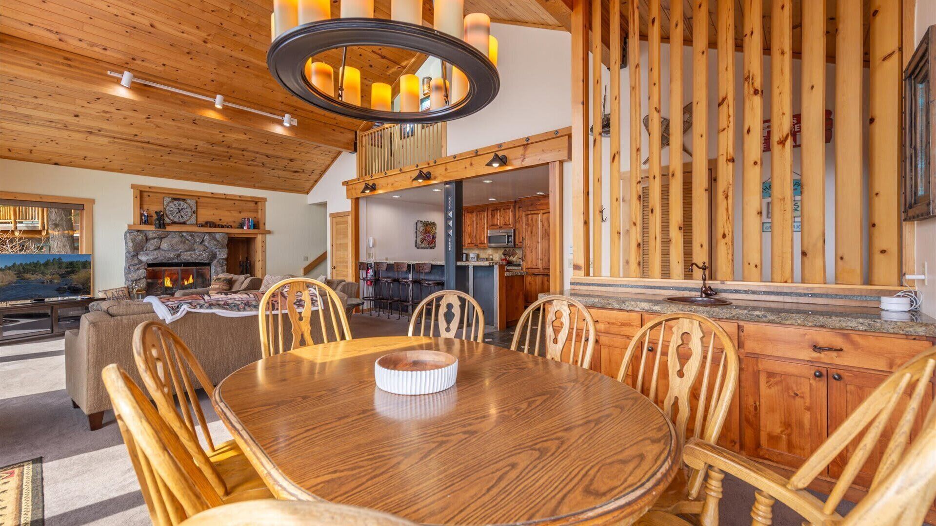 A cozy interior with a wooden dining table, chairs, a fireplace, and a kitchen area.
