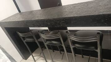 A bar area with a black countertop and three black bar stools.