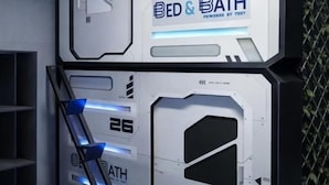 Ένα φουτουριστικό δωμάτιο με ένα κρεβάτι και μια μονάδα μπάνιου, όπου αναγράφονται οι ενδείξεις «ΚΡΕΒΑΤΙ & ΜΠΑΝΙΟ» και «ΛΕΙΤΟΥΡΓΕΙ ΜΕ ΤΕΧΝΟΛΟΓΙΑ TEST».