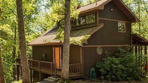 Une cabane en bois dotée d’un balcon, entourée d’arbres.