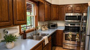 Une cuisine avec des meubles en bois, des appareils électroménagers en acier inoxydable, une fenêtre et une plante.