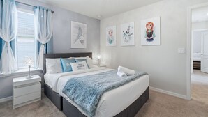 A bedroom with a bed, nightstand, lamp, and artwork on the wall. - Enchanted Palms Villa 7BR w Private Pool (Davenport)