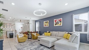 A modern living room with a sectional sofa, yellow armchairs, and a coffee table. - Enchanted Palms Villa 7BR w Private Pool (Davenport)