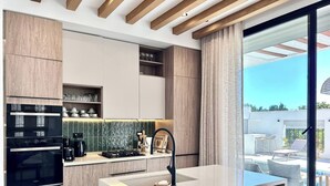 Una cocina moderna con electrodomésticos integrados, una isla central y vistas al patio exterior.