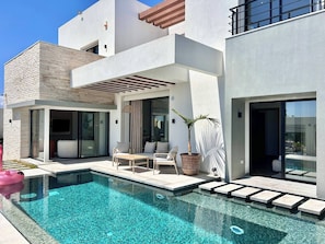 A modern house with a swimming pool, outdoor seating, and large windows. - Villa Ulysse 4 Bedroom Private Pool (Hammamet)
