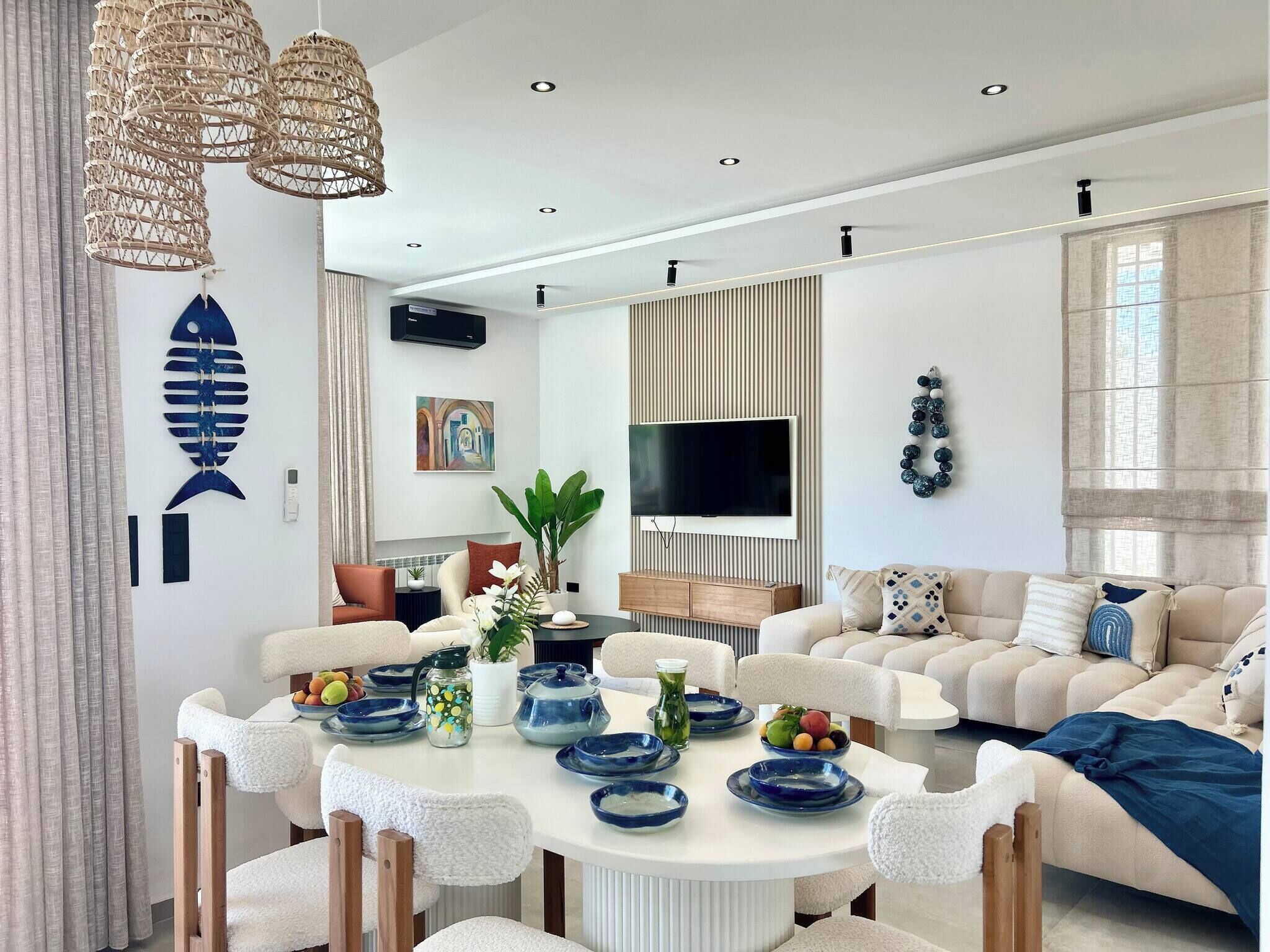 A modern living room with a round dining table, sofas, a TV, and decorative items.