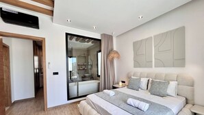 Un dormitorio moderno con una cama grande, cabina de ducha de vidrio y decoración minimalista.