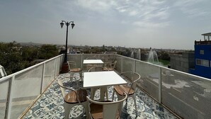 Una terraza en la azotea con mesas y sillas, un elemento de agua y vistas a la ciudad.