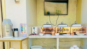 Una kitchenette pequeña con cafetera, tostadora y televisor montado en la pared.