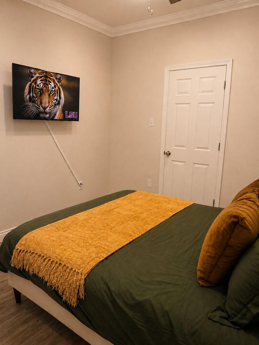 Una camera da letto con un letto, una televisione a muro e una porta.
