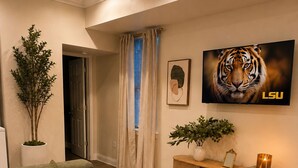 A living room with a sofa, a coffee table, a TV, and a bookshelf. - 2bed 2bath apartment in Baton Rouge 6 min. from LSU fast WiFi, and free parking (Baton Rouge)