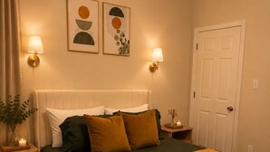 A neatly arranged bedroom with a bed, bedside lamps, a door, and wall art. - 2bed 2bath apartment in Baton Rouge 6 min. from LSU fast WiFi, and free parking (Baton Rouge)