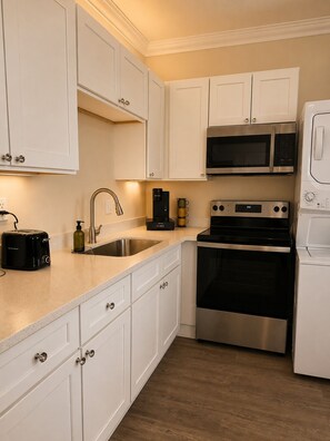 A kitchen with white cabinets, a stainless steel microwave, a coffee maker, a toaster, and a sink. - 2bed 2bath apartment in Baton Rouge 6 min. from LSU fast WiFi, and free parking (Baton Rouge)