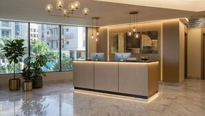 A reception desk with a modern design, large windows, and a chandelier. - La Terrasse Hotel (Jeddah)