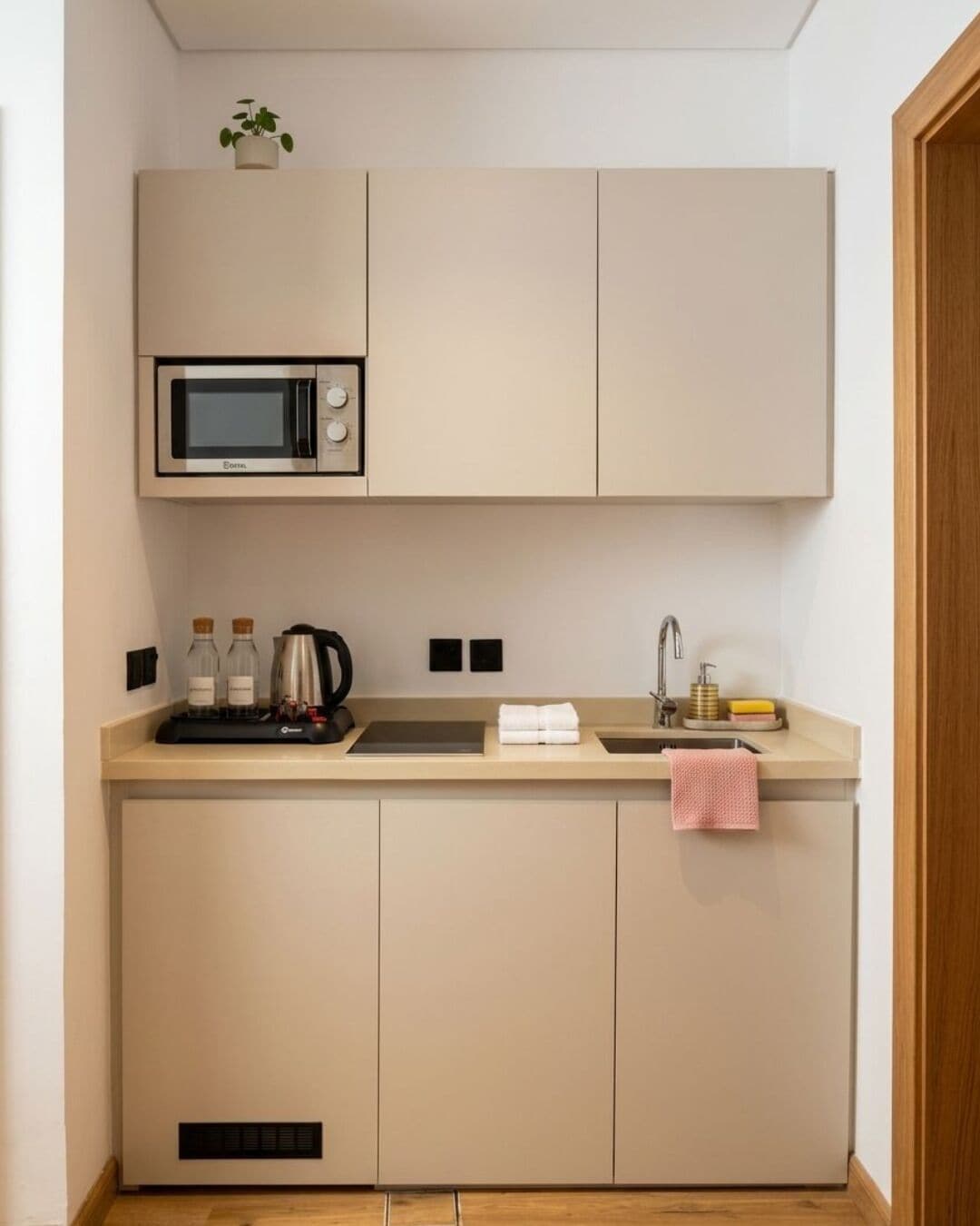 A compact kitchenette with a microwave, sink, and countertop.