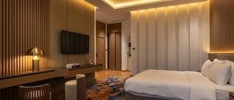 Una habitación de hotel moderna con cama, televisión, escritorio y alfombra estampada.
