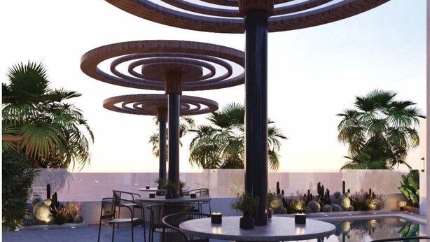 An outdoor seating area with round tables and chairs, surrounded by palm trees and cacti. - La Terrasse Hotel (Jeddah)