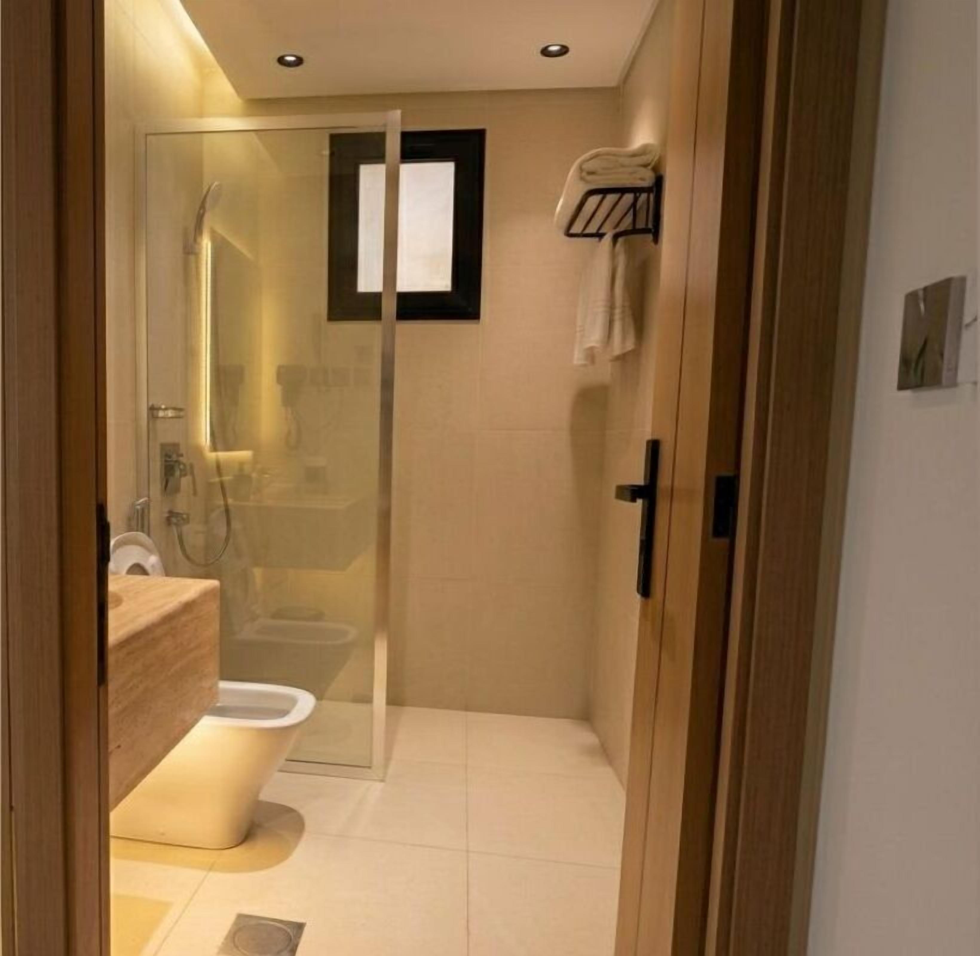A modern bathroom with a glass shower enclosure, a toilet, and a sink.