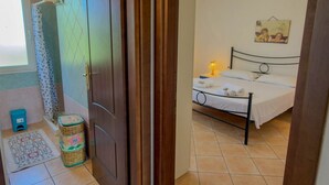 Une chambre à coucher avec un lit, une lampe de chevet, une petite table et un tableau accroché au mur.