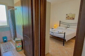Ein Schlafzimmer mit Bett, Nachttischlampe, kleinem Tisch und einem Wandbild.