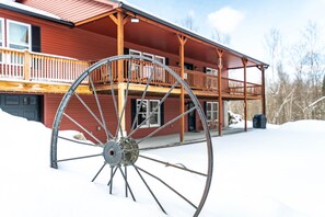 A wooden building with a balcony and a large metal wheel in front. - White Mtn Retreat on 78 Acres w/ Private Trails (Jefferson)