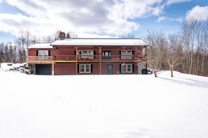 A two-story building with a balcony, a garage, and a snow-covered landscape.