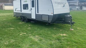Ein StarCraft Wohnmobil auf Gras mit Tür, Fenstern und sichtbarem Motor.