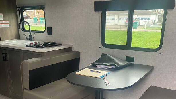 Ein kompaktes Wohnmobil-Interieur mit Küchenzeile, Essbereich und Fenster mit Ausblick nach draußen.