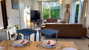 A modern living room with a TV, sofa, and dining area set up for a meal. - Holiday Home With Spacious Terrace (Sint Maartensvlotbrug)