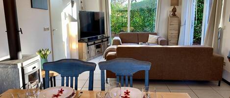 A modern living room with a TV, sofa, and dining area set up for a meal.