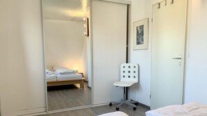 A hotel room with a bed, a chair, a bedside table, a wardrobe, and a door. - Holiday Home With Spacious Terrace (Sint Maartensvlotbrug)