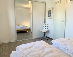 Ein Hotelzimmer mit Bett, Stuhl, Nachttisch, Kleiderschrank und Tür.