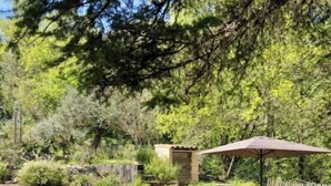 Un patio con una mesa de shuffleboard, un área de comedor con sillas y una sombrilla, y un muro de piedra.