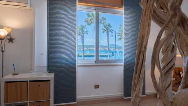 A room with a large window, a white cabinet, and a decorative wooden sculpture. - Stella Cadente – Sea view retreat just steps from the beach (Golfo Aranci)