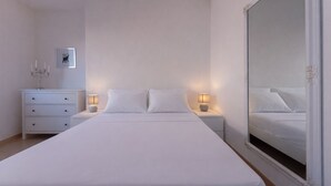 A bedroom with a large bed, bedside tables, a nightstand, a wall-mounted picture, and a mirror. - Stella Cadente – Sea view retreat just steps from the beach (Golfo Aranci)