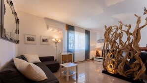 A modern living room with a sofa, a small table, and a decorative wooden sculpture. - Stella Cadente – Sea view retreat just steps from the beach (Golfo Aranci)