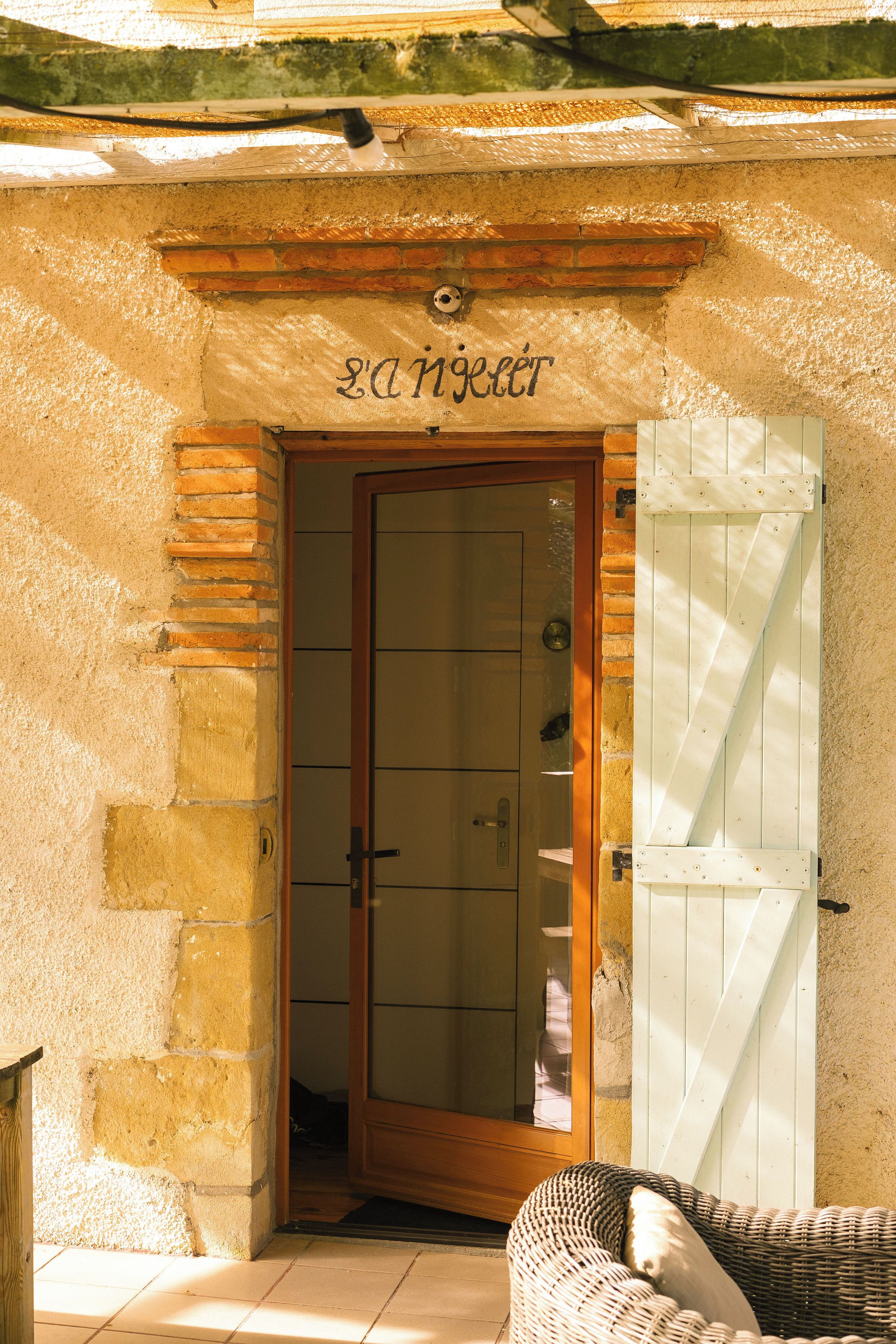 A doorway with a wooden frame and glass panels, leading to a room with a wicker chair and a white door.