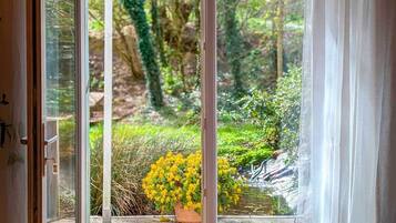 A room with a sliding glass door leading to a garden with yellow flowers and greenery.