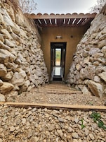 Un pasillo de paredes de piedra que conduce a un acceso con vistas a un paisaje verde.