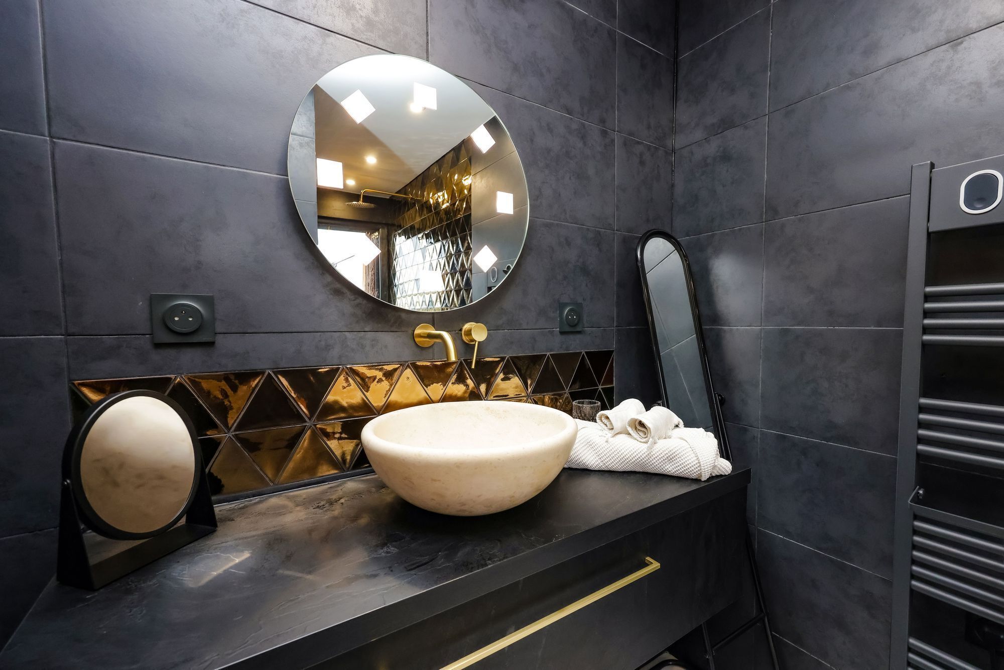 A modern bathroom with a round mirror, a beige sink, and a towel rack.