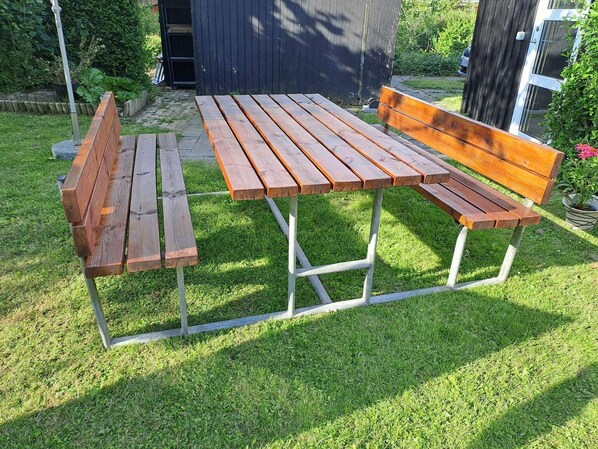 A wooden picnic table with benches, set on a grassy lawn. - 4 Star Holiday Home in Nakskov (Nakskov)