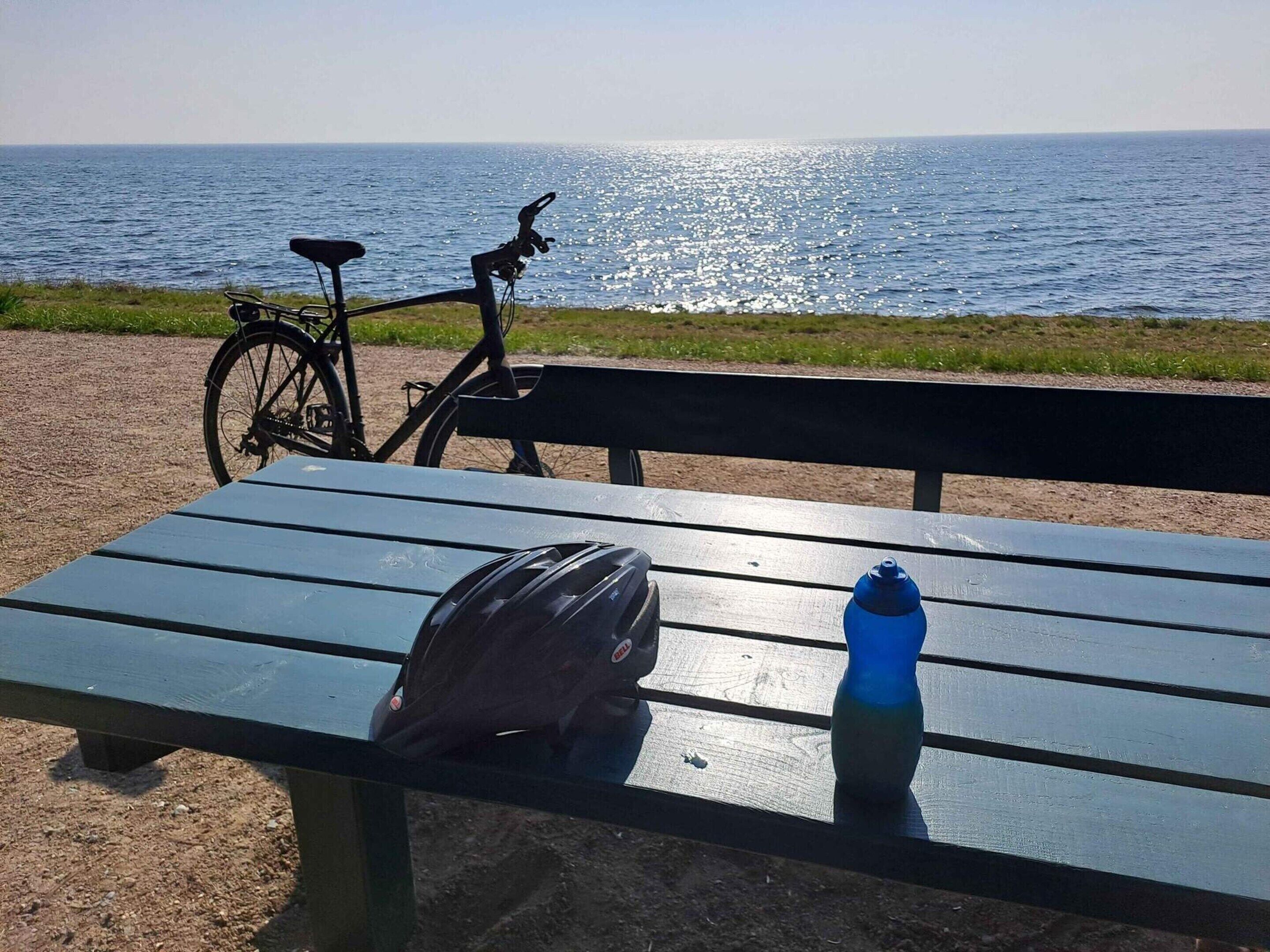 A bench with a bicycle and a water bottle on it.