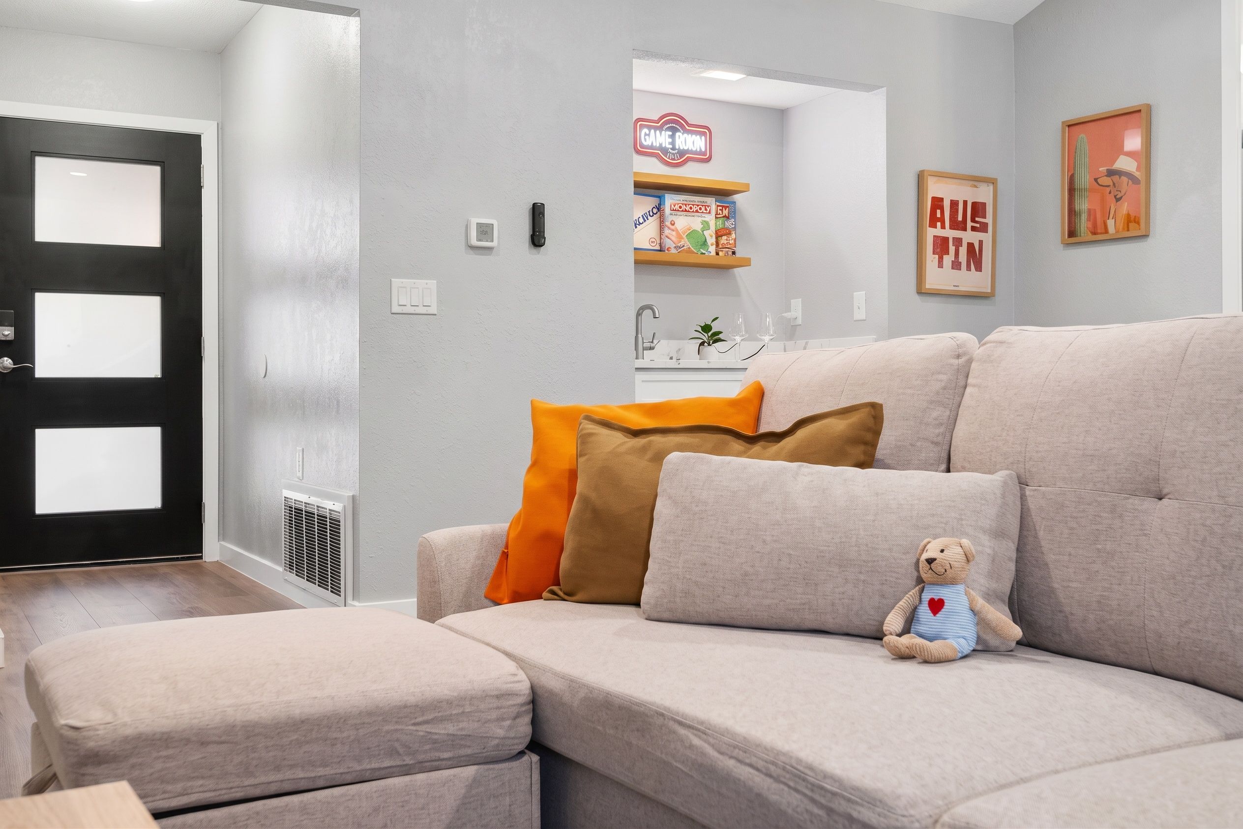 A living room with a sofa, a teddy bear, and a Game Rookin sign.