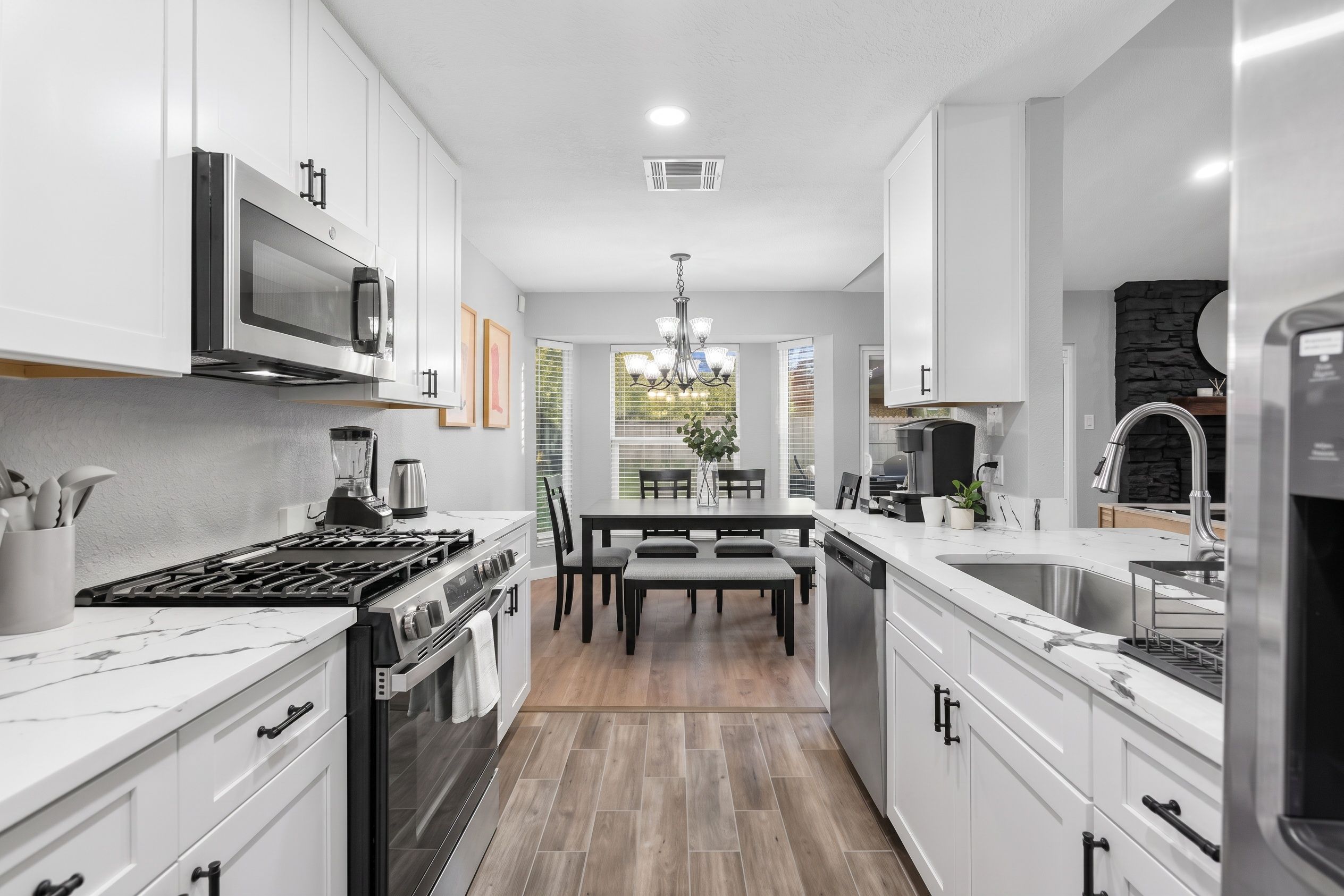 A modern kitchen with white cabinetry, a built-in microwave, a gas stove, and a stainless steel sink.