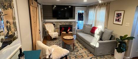 A living room with a fireplace, a sofa, a coffee table, and a TV mounted on the wall.