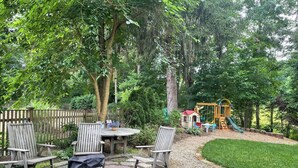 Un'area patio con tavolo e sedie, circondata da una recinzione in legno e alberi.