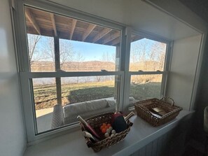 A window with a view of a rural landscape, two wicker baskets on a ledge, and a cushion. - Welcome to The McCormick House (West Point)