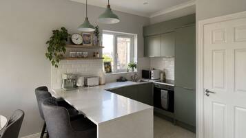 A modern kitchen with a central island, bar stools, and a window providing natural light.