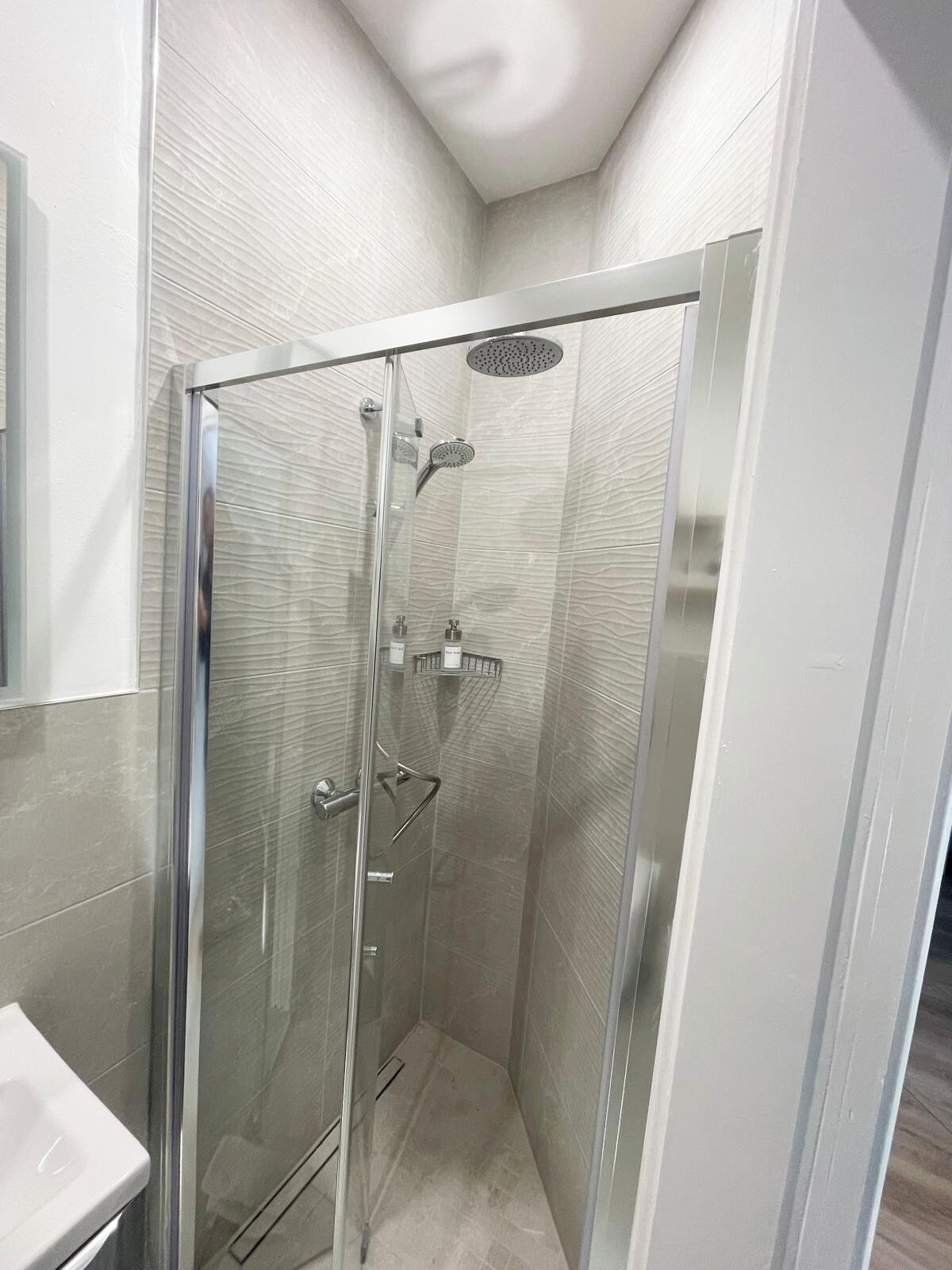 A modern bathroom with a glass-enclosed shower, a white sink, and a mirror.